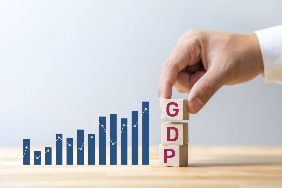 Man Holding Wooden Cubes That Represent GDP With Graph