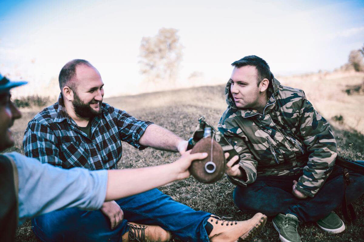 Hunters sit in a field, smiling and fist-bumping one another, as they celebrate a successful hunt in Montana