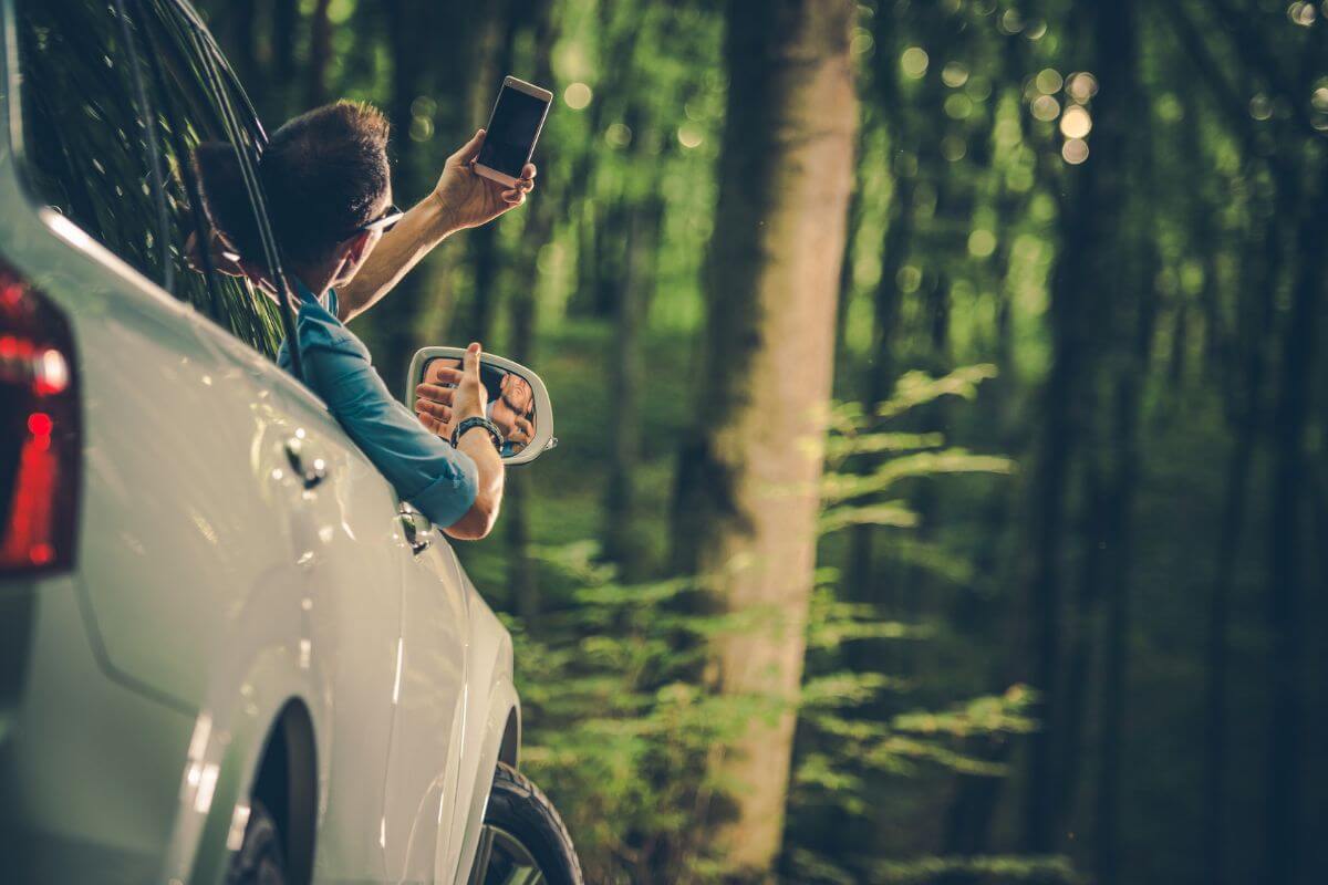 A Man in His Car Having Trouble Finding a Signal for His Cellphone in a Montana Forest