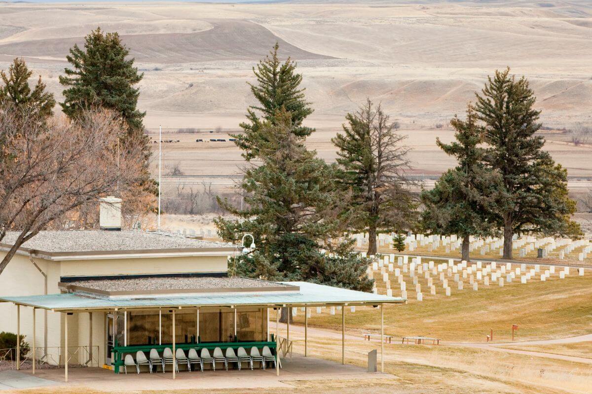 A small building in the middle of a grassy field in front of a graveyard at Little Bighorn Battlefield National Monument, Montana.