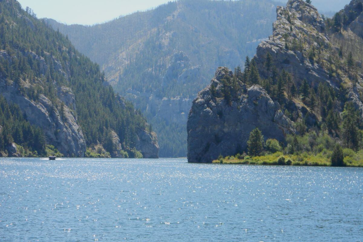 A boat is cruising on a river with mountains in the background at the Gates of the Mountains, Montana.