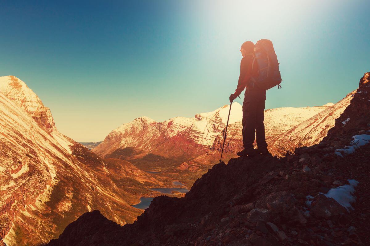 A man trekking the Montana mountains stops to take in the view below him.