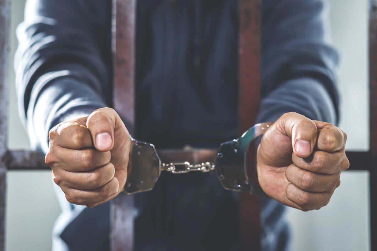Man Inside a Jail Cell with Handcuffs