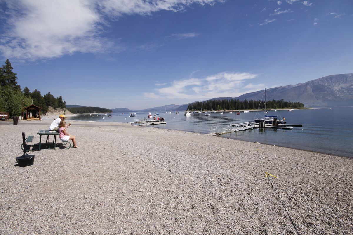 A group of people sitting on a bench on a lake  in Montana.