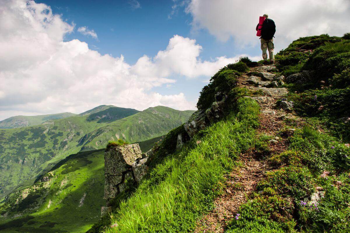 A man enjoying the breathtaking view from a mountain trail in Montana during his adventurous vacation.