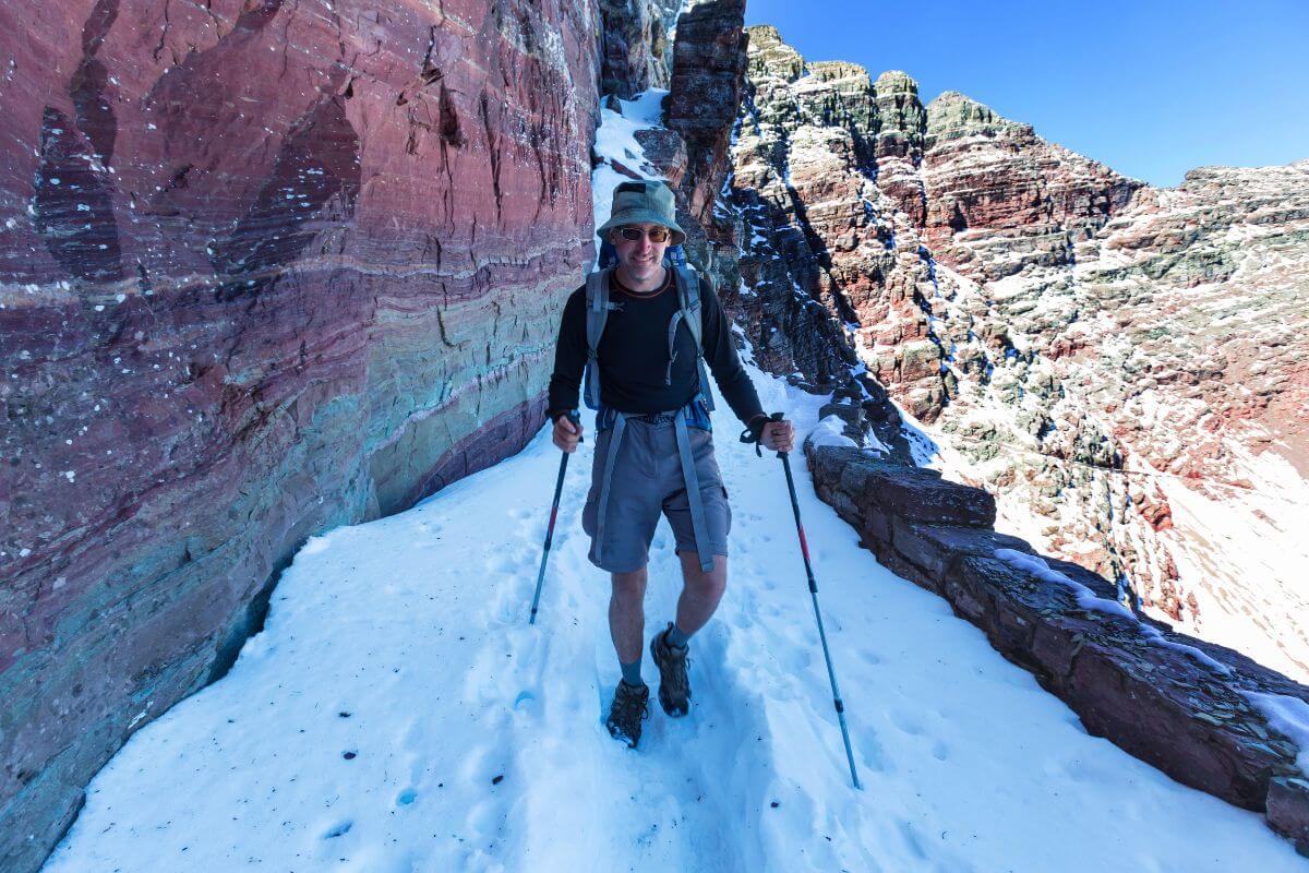 A man with ski poles walking a snowy trail in a mountain in Montana.