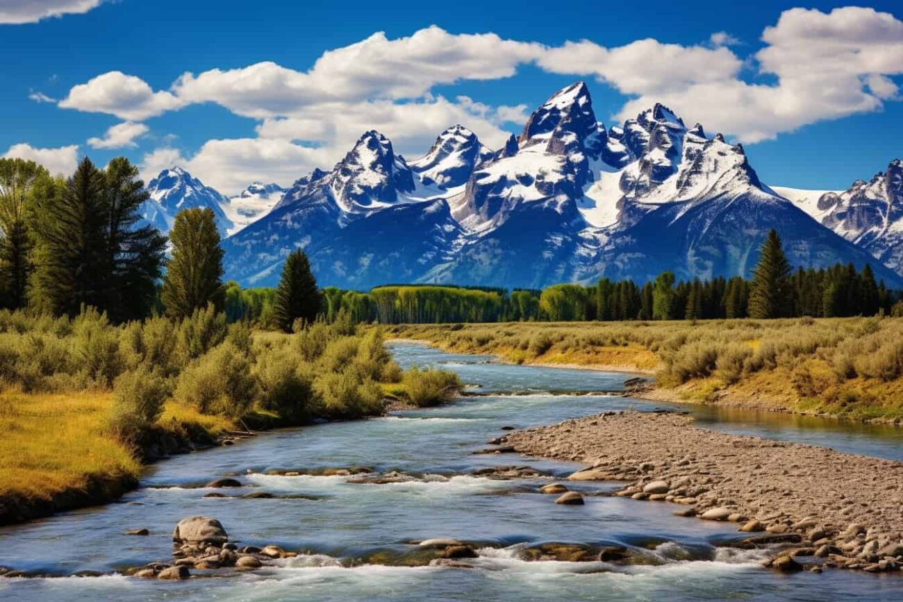 Snow-capped mountain range in Montana with a river in the background.